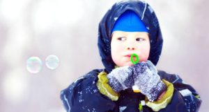 Baby playing with ice bubbles during winter outdoors.