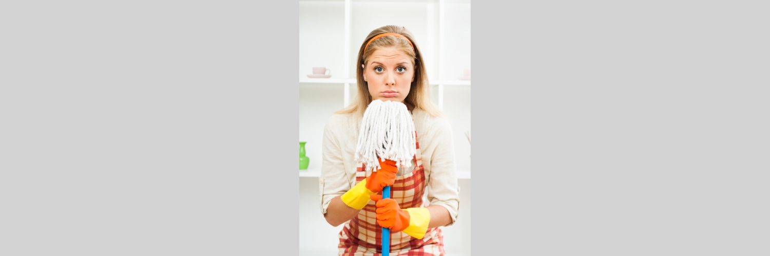 Smiling woman cleaning a bright living room with flowers and sunlight, representing happier spring cleaning.