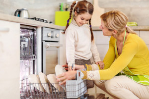 Mother and daughter using dishwasher.