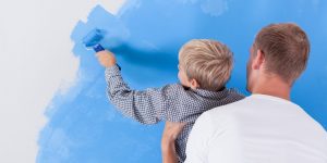A man and a child painting a wall together during a home improvement project.