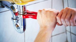 DIY home plumbing repair with wrench tightening pipe under sink