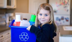 Small girl using recycled household items for a creative project at home