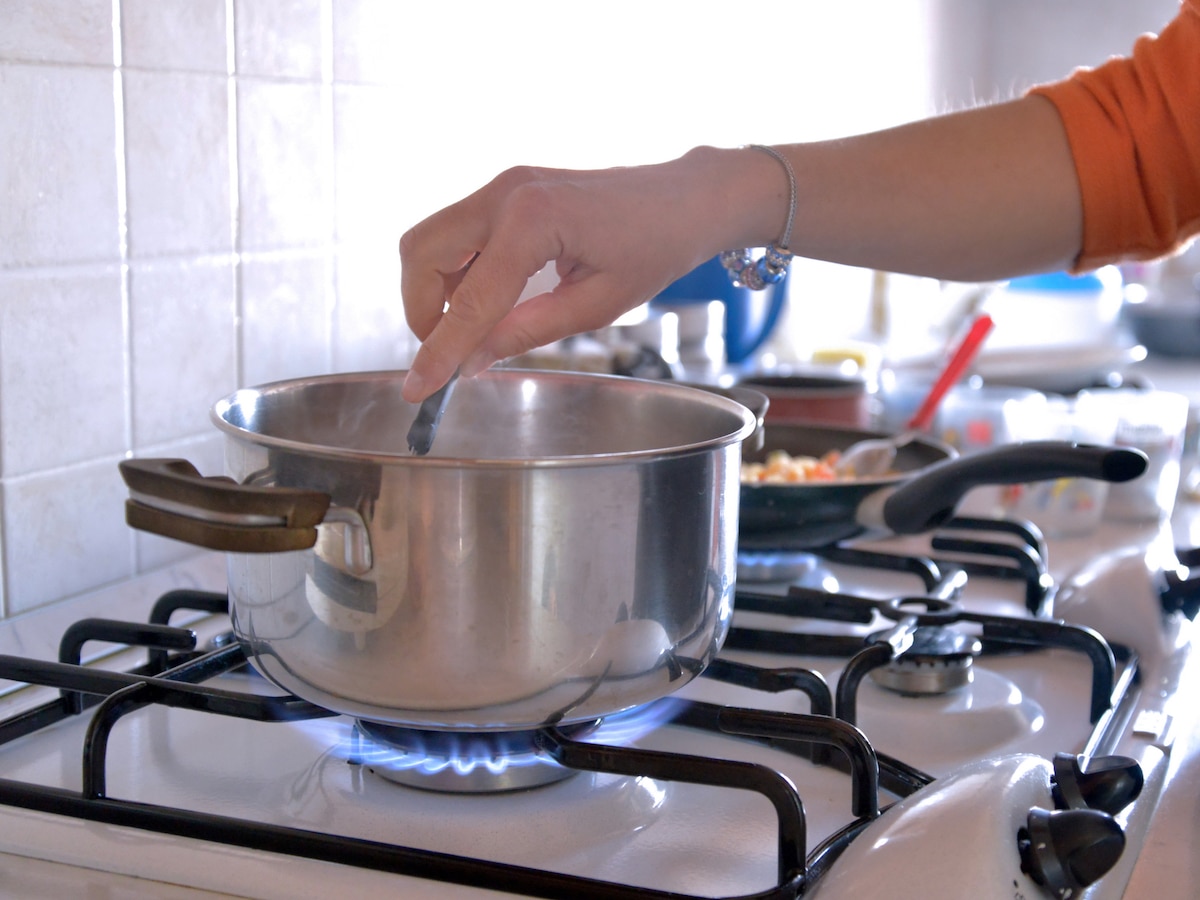 Cooking on a gas stove showing blue flame and stainless-steel cookware
