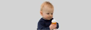 Baby reaching for colorful bottles on a low shelf, highlighting poison prevention awareness.
