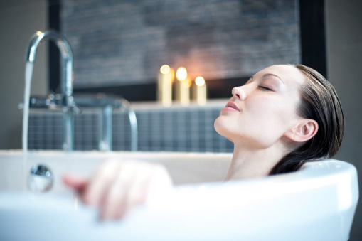 Girl taking a relaxing bath in a bathtub using hot water from a high-efficiency water heater