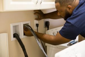 Plumber inspecting damaged pipes under a sink.