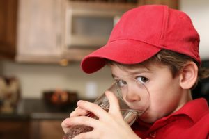Small boy drinking a glass of water at home.