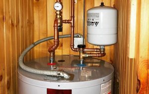 Small water heater expansion tank mounted above a residential water heater.