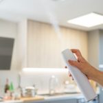 woman's hand spraying air freshener into the air at home
